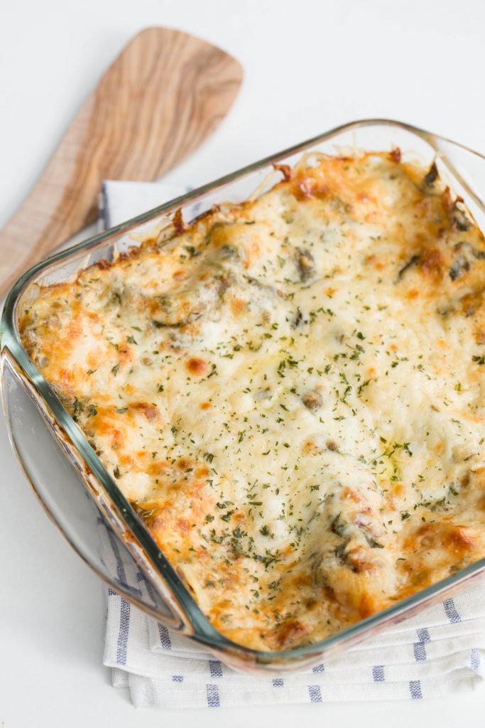 Spinach Dip Lasagna in a baking pan standing on a kitchen towel