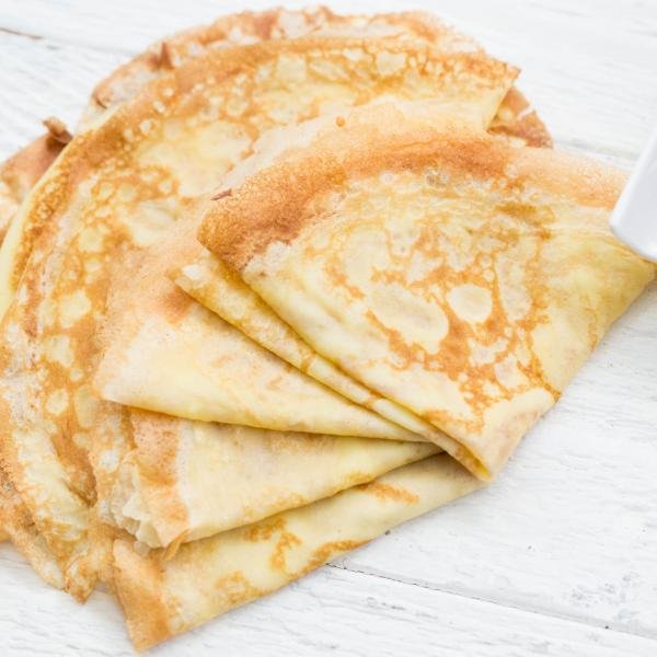 Perfect Crepes on a table with a bowl of jam besides it