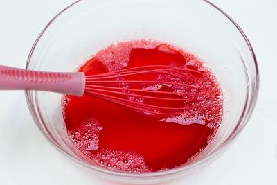 Strawberry Jello being mixed in a bowl with a whisk