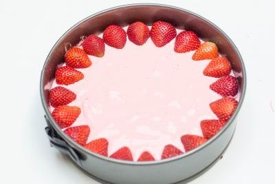 Strawberry halves placed around the circumference of the Strawberry Jello Cake Dessert in the baking pan