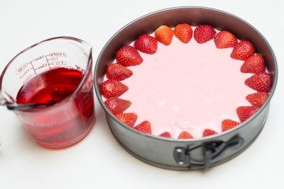 Strawberry Jello Cake Dessert in a cake baking pan and a measuring cup with jello mixture
