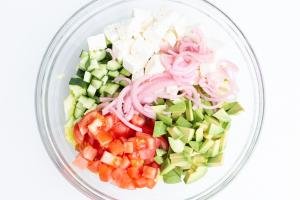 Diced tomatoes, cucumber, avocado, romaine lettuce, pickled onions and feta in a bowl