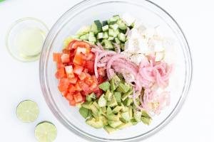 Salad in a bowl with 2 lime halves and avocado oil in a bowl besides the salad