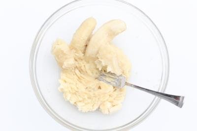 Banana being mashed in a bowl with a fork