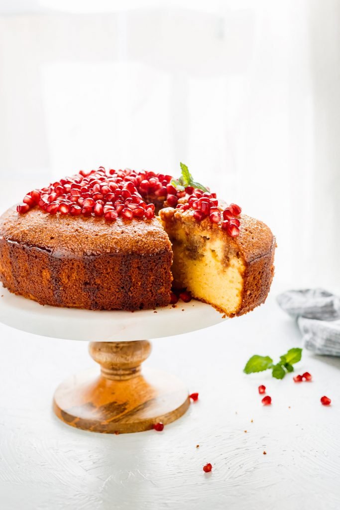 Orange Almond Cake on a serving tray with a slice being pulled out