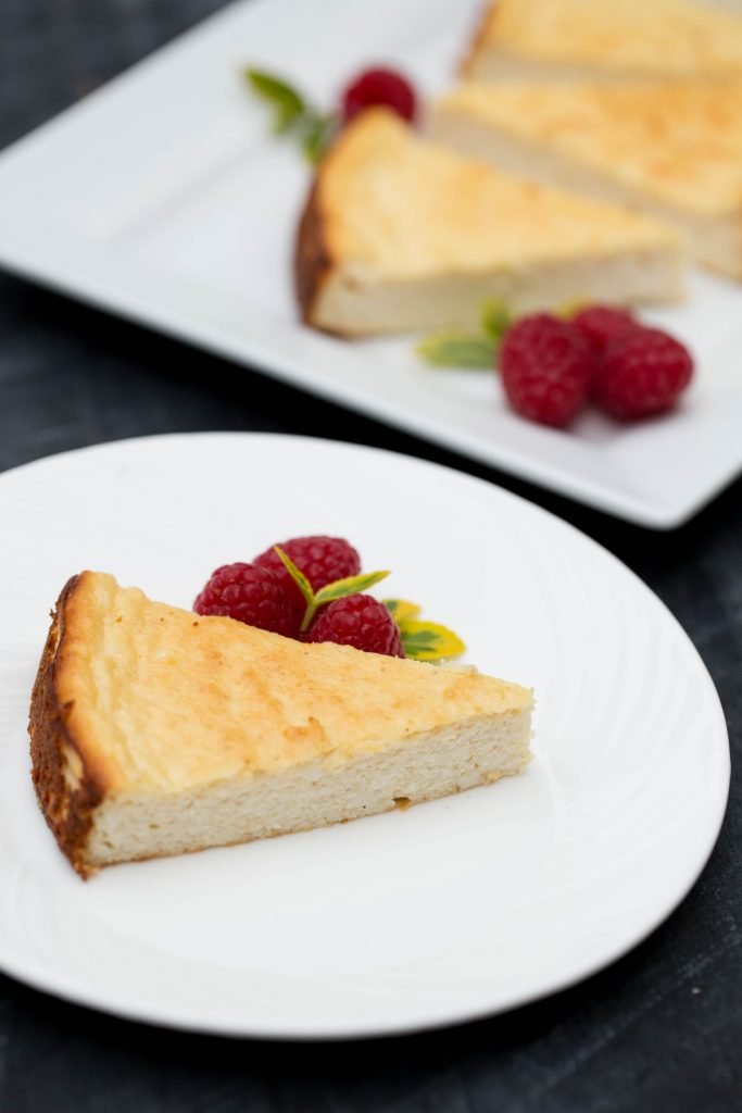 Farmers Cheese Coffee Cake slice on a plate with raspberries besides the slice