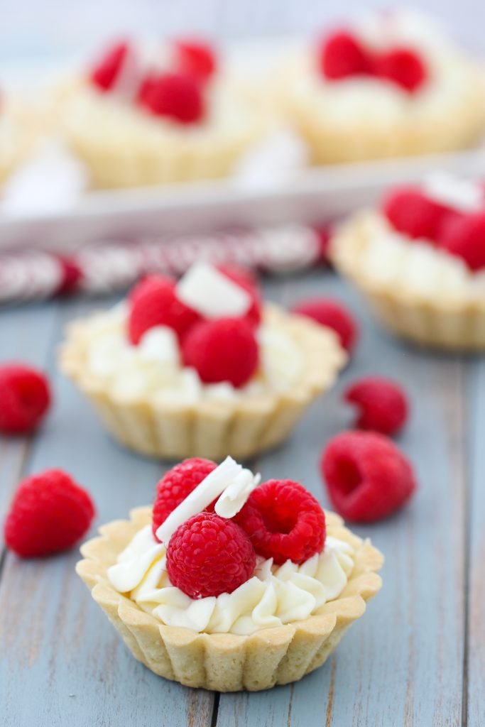 Tarts with raspberries on wood board