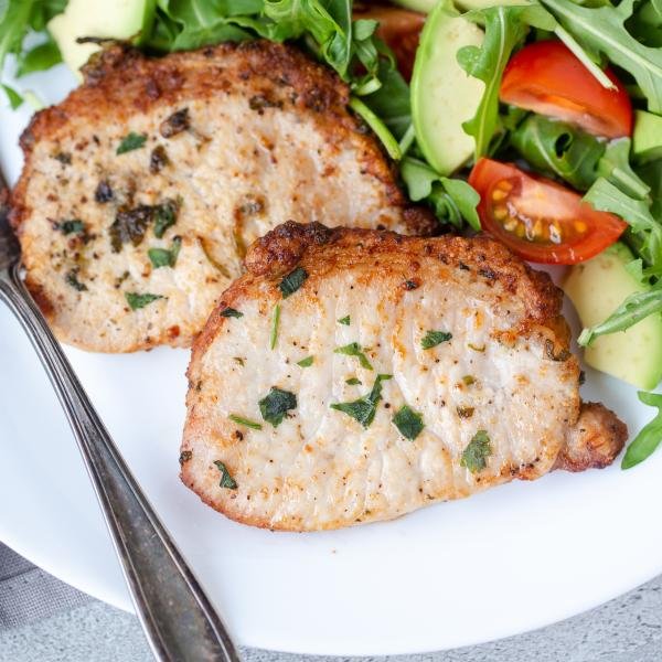 Plate with fork, pork chops and salad