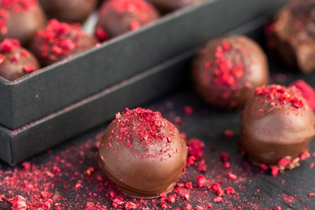 Raspberry truffle on a tray with box of truffles in the background