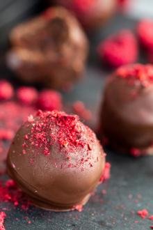 Raspberry truffle on a tray with box of truffles in the background