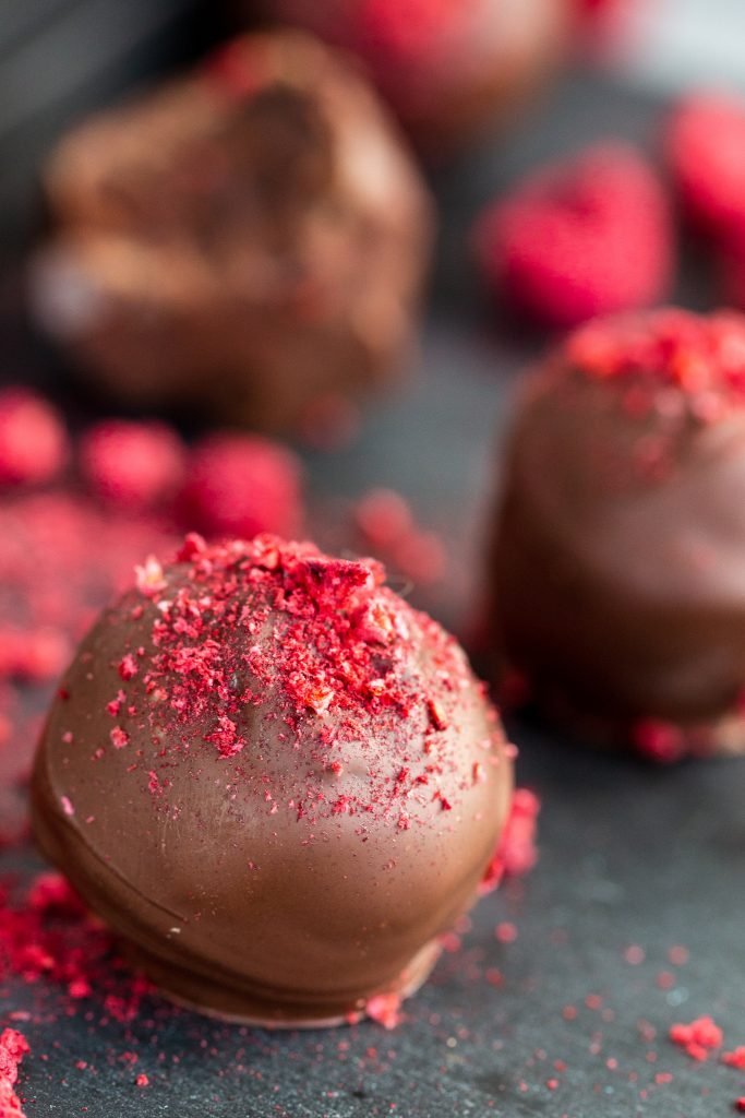 Raspberry truffle on a tray with box of truffles in the background