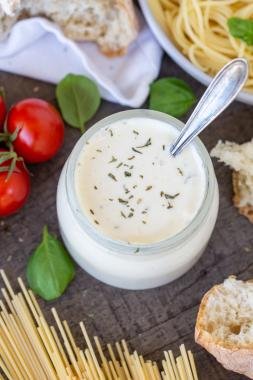 Easy Homemade Alfredo Sauce in a jar with parmesan with bread and pasta