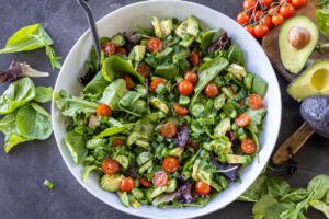 Garden Salad in a bowl with serving spoon with veggies around it.