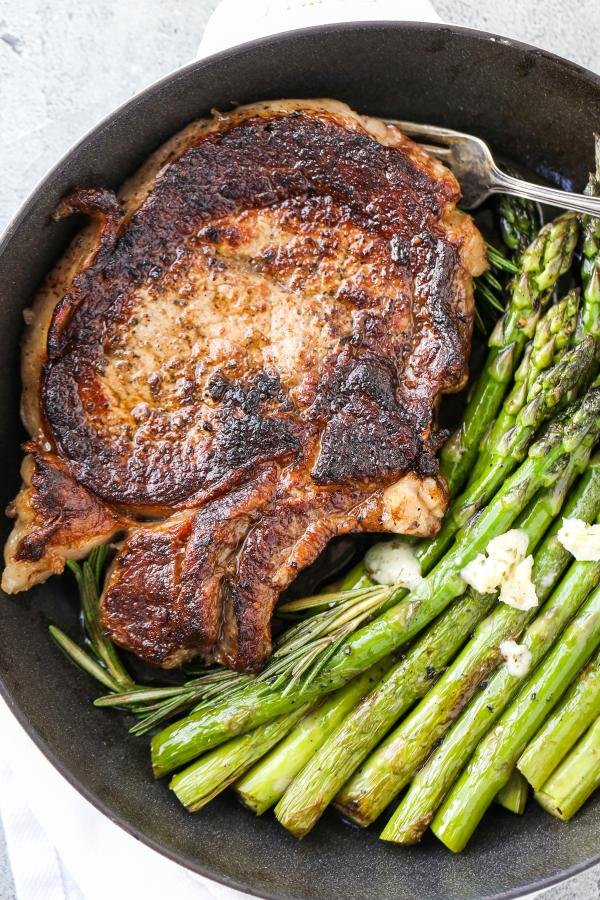 Ribeye cooked in a cast iron pan with asparagus