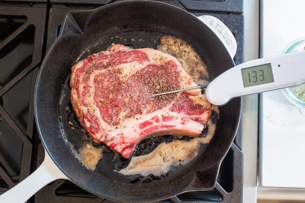 Ribeye in a pan with butter and thermometer
