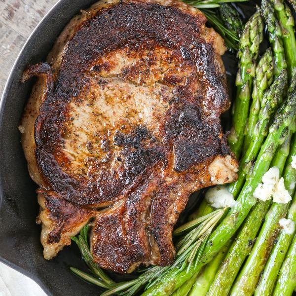 Cooked Ribeye in a cast iron skillet with asparagus