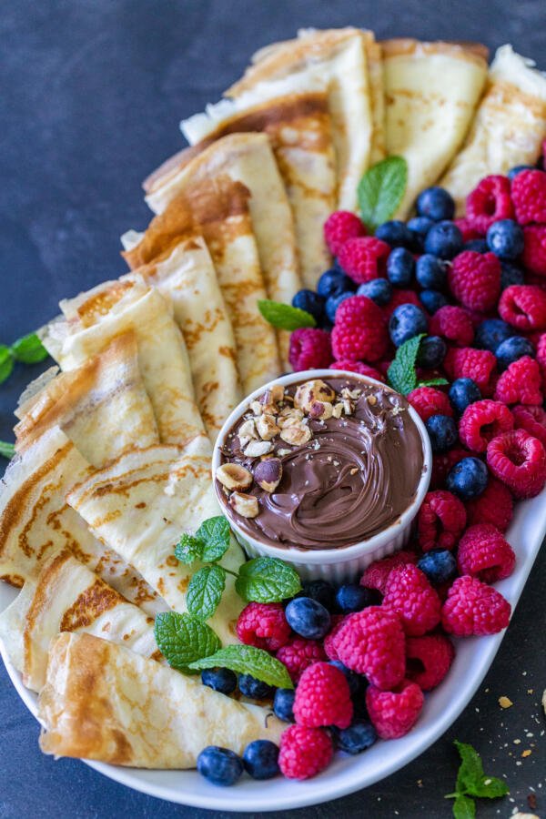 Crepes on a tray with fruits and Nutella