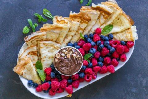 Crepes on a tray, berries and nutella