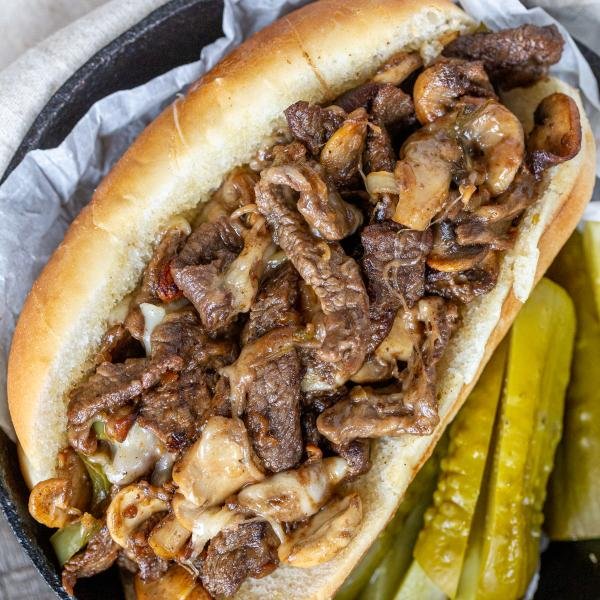 Philly Cheesesteak Sandwich in a tray with pickles