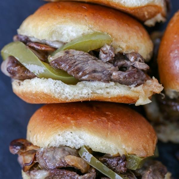 Philly Cheesesteak Sliders stacked on a board