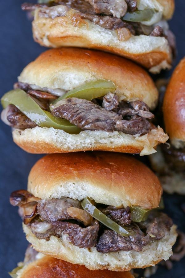 Philly Cheesesteak Sliders stacked on a board