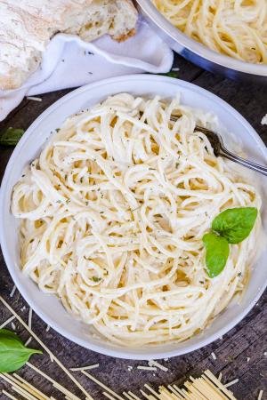 Alfredo Pasta in a bowl with pasta ingredients around