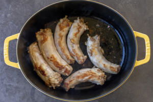 Turkey necks frying in a pan.
