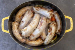 Turkey necks, carrot, onion in a pan.