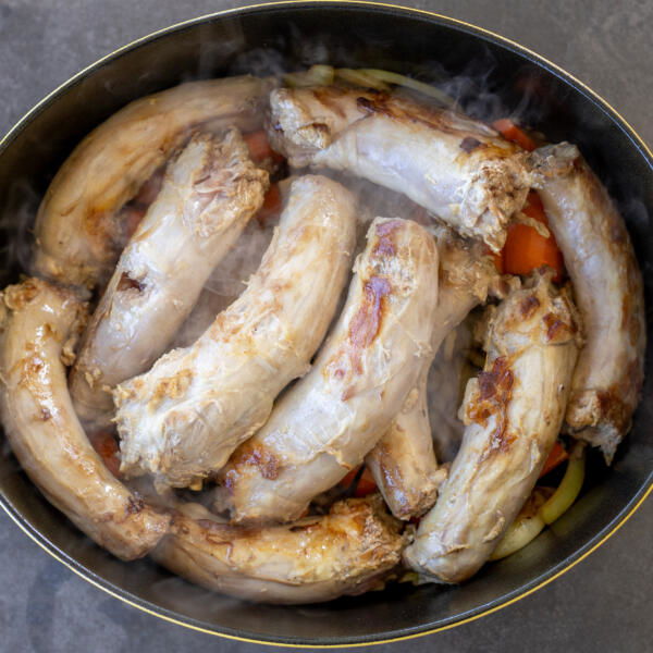 Turkey necks, carrot, onion in a pan.