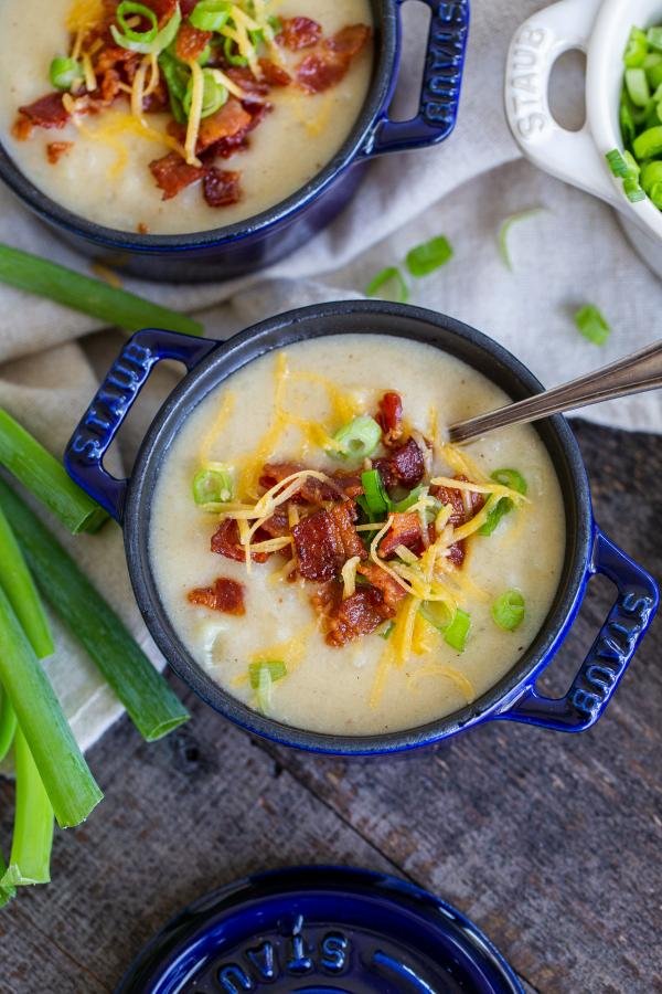 cremosa zuppa di patate in una ciotola con pancetta, formaggio e cipolle verdi 