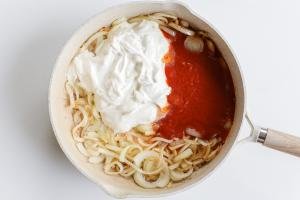 Onion sour cream and tomato sauce in a pan