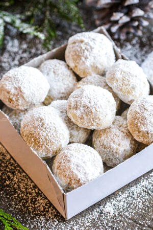 Snowball Cookies in a box with powder around.