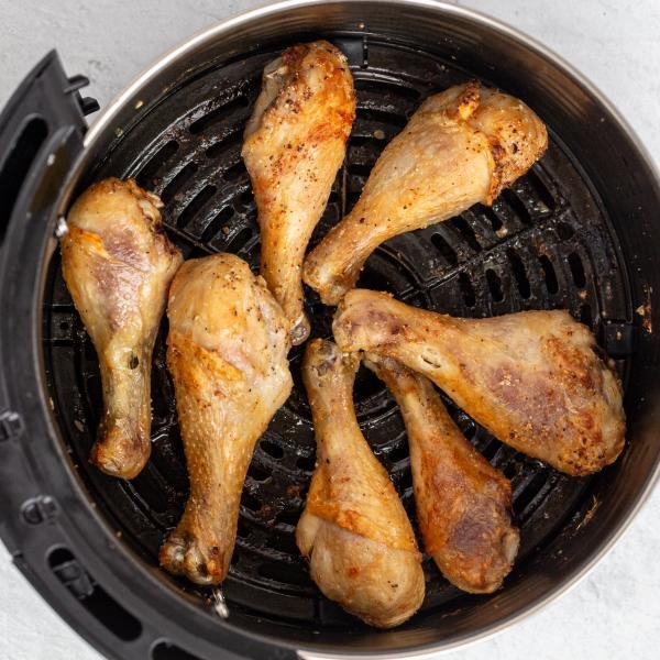 cooked chicken legs in an air fryer basket