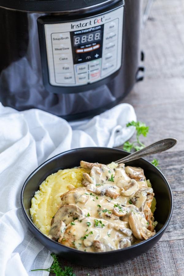 Creamy chicken and mushrooms over potatoes next to intant pot