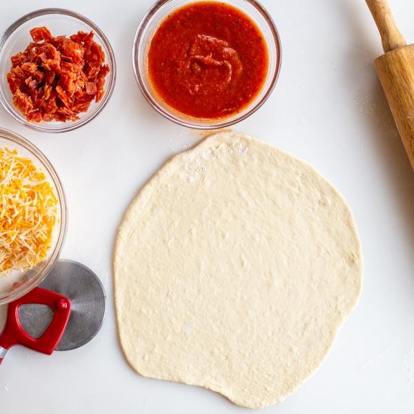 Rolled out pizza dough and fillings for pizza