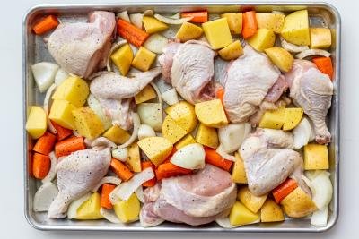 Raw chicken and potatoes on a baking sheet