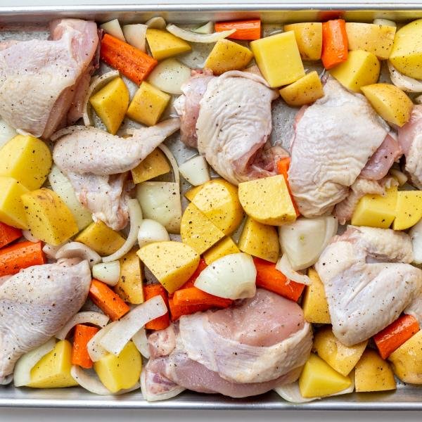 Raw chicken and potatoes on a baking sheet