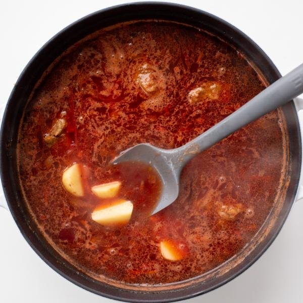Potatoes added to a pot with borscht