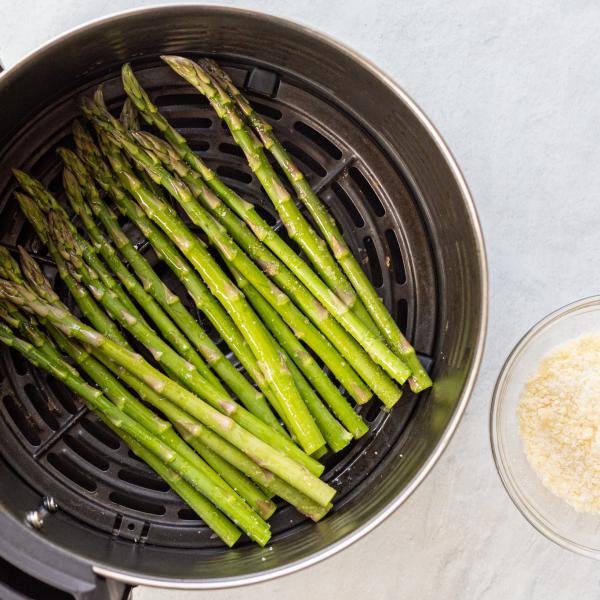 air fryer basket with raw asparagus