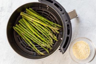 air fryer basket with raw asparagus