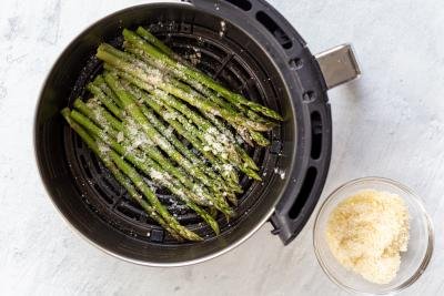 raw asparagus with parmesan in an air fryer basket