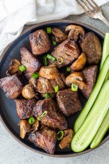 Air fryer steak bites in on a plate with cucumbers
