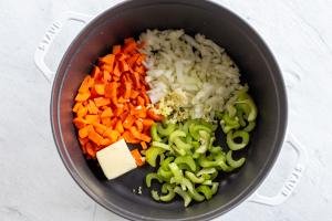a pot with carrots, celery, onion, butter and garlic