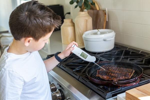 a boy checking temperature of the meat