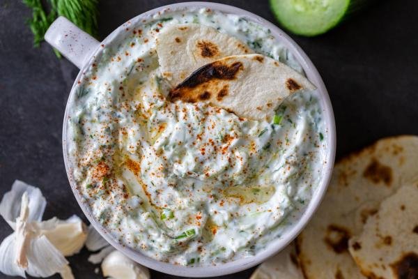 A bowl of Tzatziki sauce with a dipped tortilla