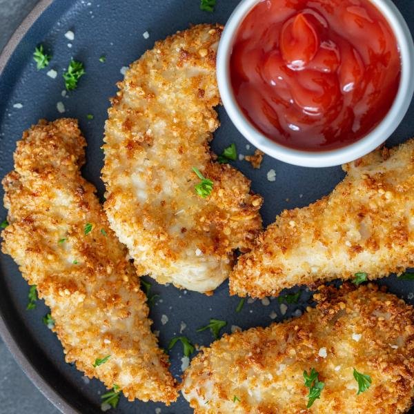 Air fryer chicken tenders on a plate with ketchup