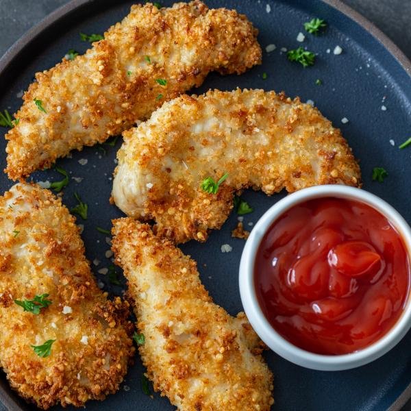 Air fryer chicken tenders on a plate with ketchup
