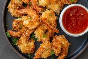 crispy air fryer coconut shrimp on a plate with a sauce