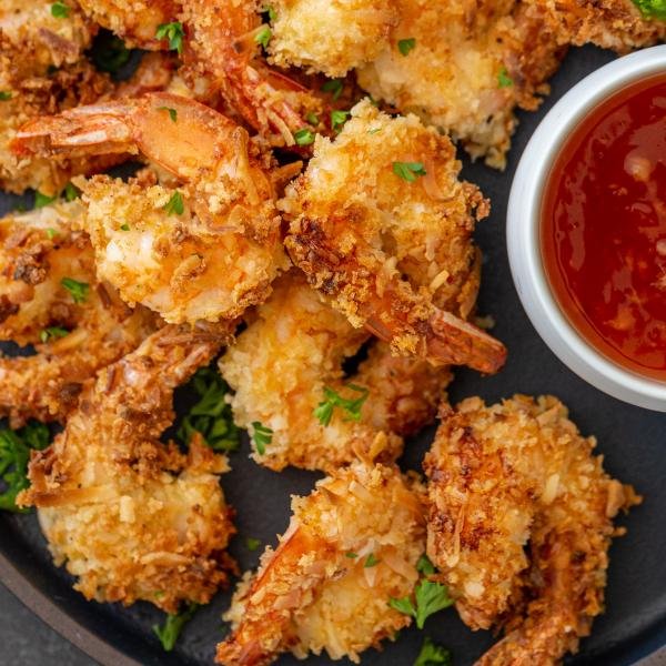crispy air fryer coconut shrimp on a plate with a sauce