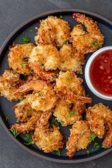 crispy air fryer coconut shrimp on a plate with a sauce